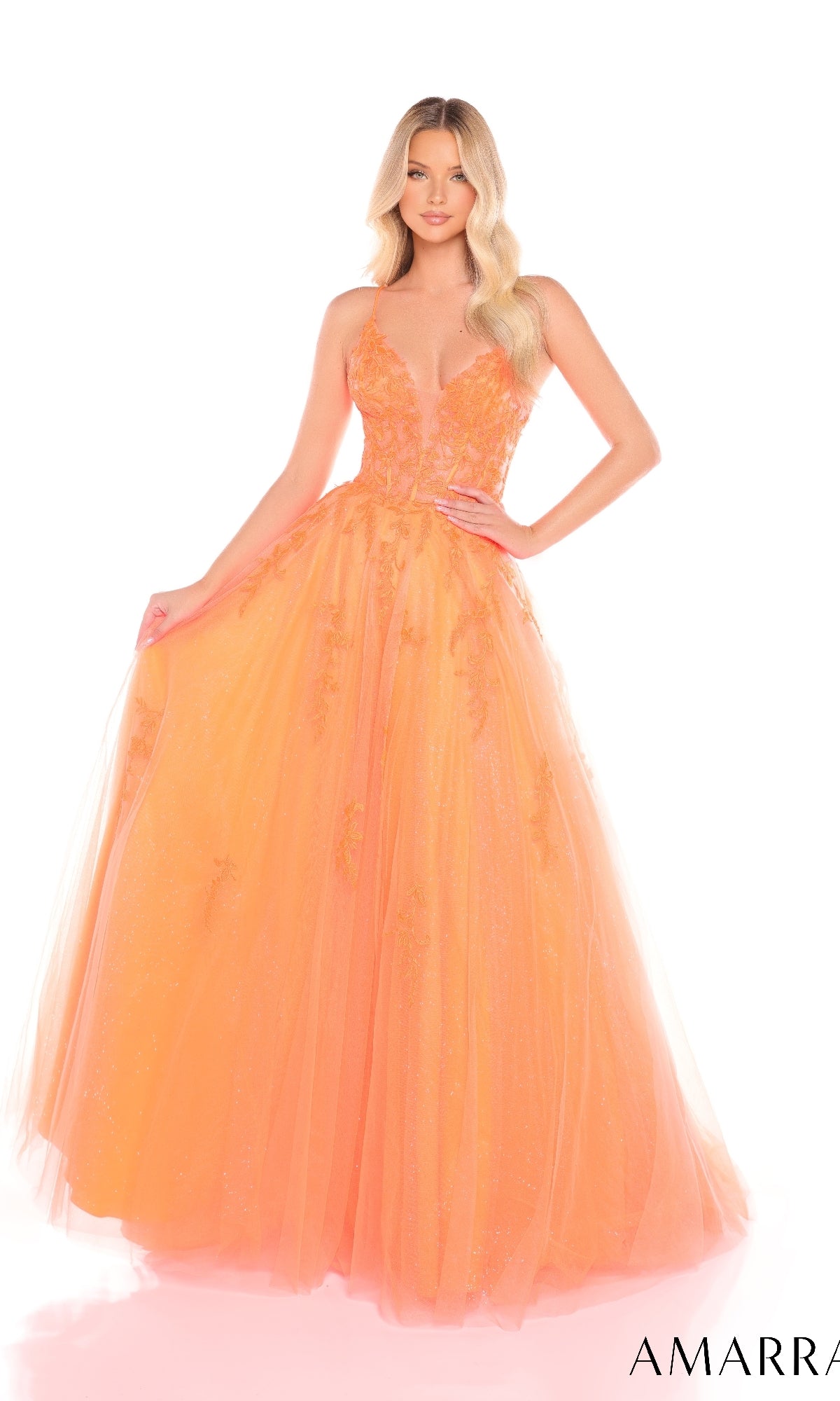 A woman wears the Amarra 88410, a sleeveless, floor-length orange prom ball gown with floral details, a deep V-neckline, and a corset bodice, standing against a white background.